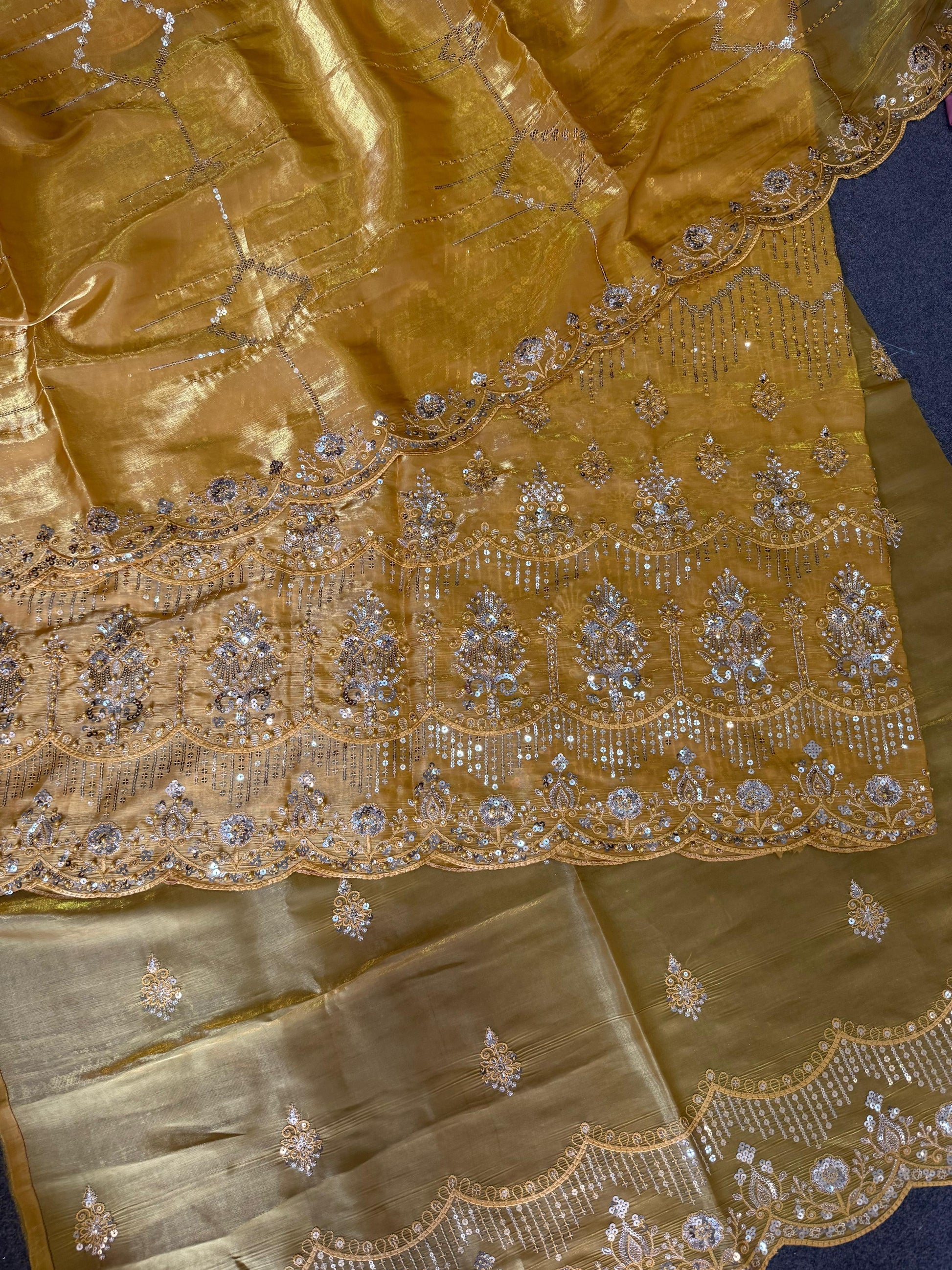 Gold saree with intricate silver embroidery on a blue background